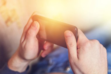 Adam kanepede onun elinde telefon ile yatıyor.