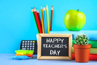 Bir kara tahta üzerinde metin tebeşir: mutlu öğretmenin gün. Okul malzemeleri, ofis, kitaplar, elma.