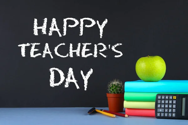 Tekst krijt op een schoolbord: Happy Teacher's Day. Schoolbenodigdheden, kantoor, boeken, appel. — Stockfoto
