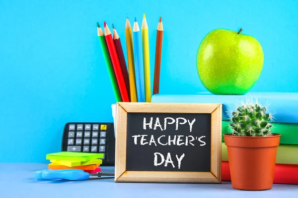 Bir kara tahta üzerinde metin tebeşir: mutlu öğretmenin gün. Okul malzemeleri, ofis, kitaplar, elma.