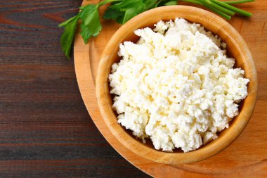 Ahşap bir masa üzerinde bir kasede ev süzme peynir.