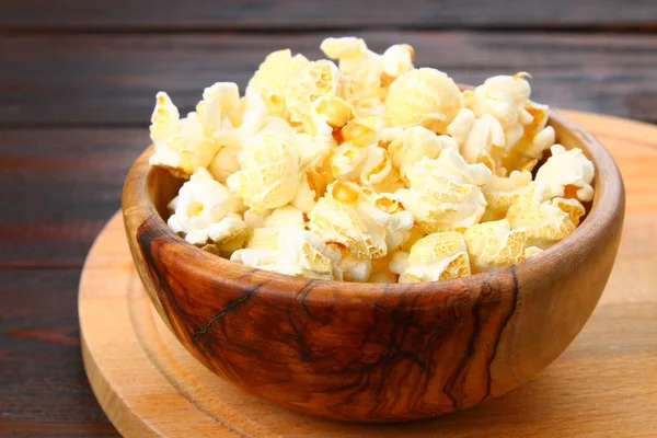 Gezouten popcorn in een houten kom op een houten tafel. — Stockfoto