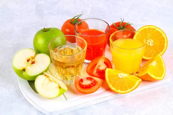 Óculos com laranja fresca, maçã, suco de tomate em uma mesa de concreto cinza. Lóbulos Frutas e legumes ao redor . — Fotografia de Stock