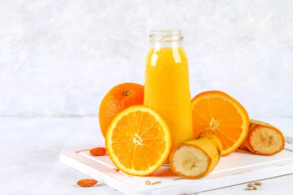 Orange smoothies from orange, banana on a gray concrete table.