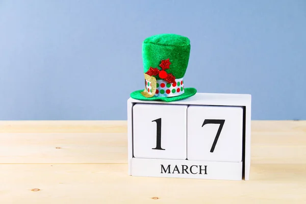 Un sombrero verde sobre una mesa de madera. Día de San Patricio. Un calendario de madera que muestra 17 de marzo . — Foto de Stock