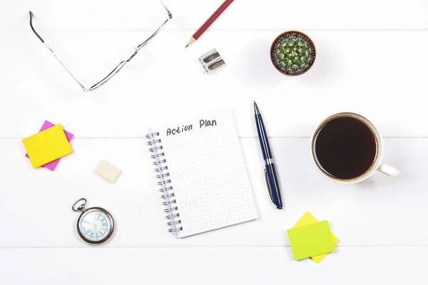 Bloc-notes avec le texte : plan d'action. Table blanche avec horloge, cactus, papier pour notes, tasse à café, stylo, verres . — Photo