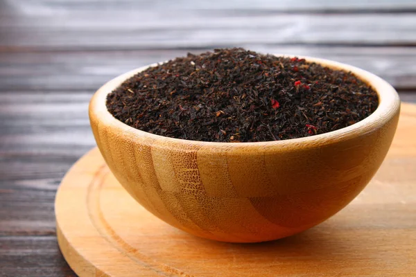 Trockener schwarzer Tee mit Kirsche in einer Schüssel auf einem Holztisch. — Stockfoto