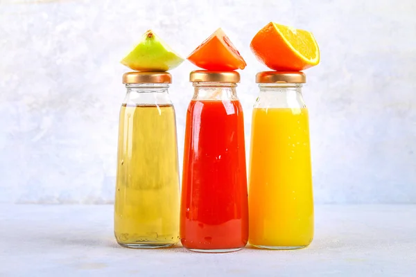 Botellas con naranja fresca, manzana, jugo de tomate sobre una mesa de hormigón gris. Lobulillos Frutas y verduras alrededor. Vista superior. Piso Lay . — Foto de Stock