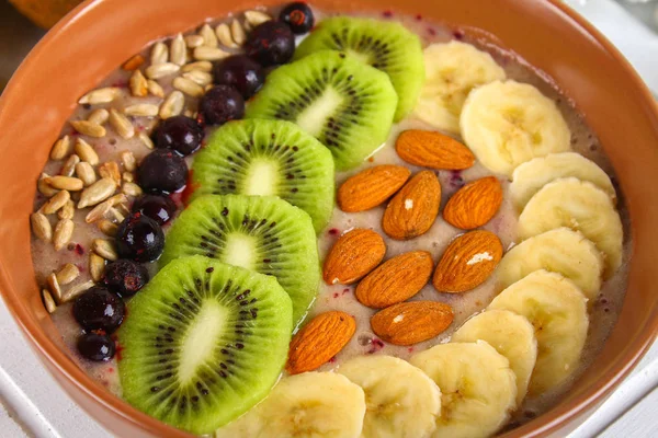 Чаша фруктового коктейля на завтрак с бананами, ягодами, киви, миндалем и семечками подсолнечника . — стоковое фото