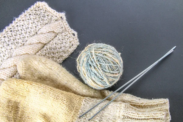 Ein Wollknäuel mit Stricknadeln und Socken auf einem grauen Tisch. Handarbeit. — Stockfoto