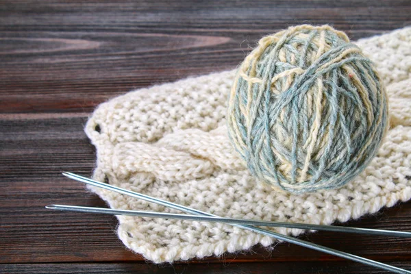 Ein Wollknäuel mit Stricknadeln und gestrickten Socken auf einem Holztisch. Handarbeit. — Stockfoto