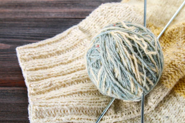 Uma bola de lã com agulhas de tricô e meias de malha em uma mesa de madeira. Agulha . — Fotografia de Stock