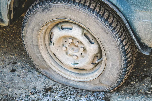 Κατεστραμμένο σκασμένο λάστιχο του ένα παλιό αυτοκίνητο στο δρόμο με επιλεκτική εστίαση. — Φωτογραφία Αρχείου