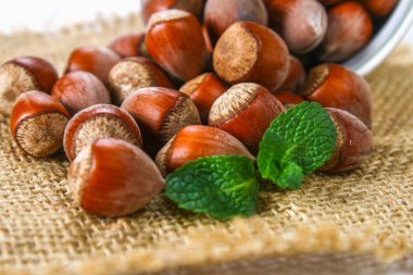 Beyaz ahşap bir masa üzerinde çul üzerinde dağınık ceviz fındık.