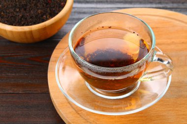 Siyah çay bir cam fincan sıcak ve kuru çay ahşap bir masa üzerinde.
