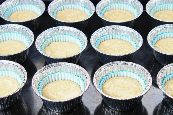 Massa de farinha em moldes de bolos em uma mesa de madeira . — Fotografia de Stock