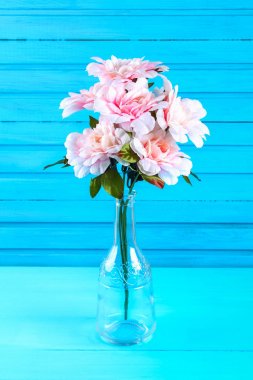 Pembe peonies mavi ahşap bir masa üzerinde bir şişe. Kartpostal tatil için.