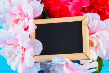 Pembe peonies mavi ahşap bir masa bir kara tahta ile. Kartpostal tatil için. Kopyalama alanı.