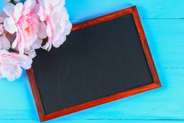 Pembe peonies mavi ahşap bir masa bir kara tahta ile. Kartpostal tatil için. Kopyalama alanı.