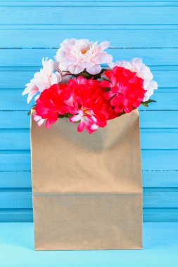 Pembe peonies mavi ahşap bir masa üzerinde bir zanaat paketindeki. Kartpostal tatil için.