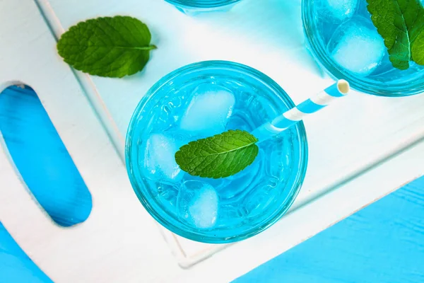 Cóctel azul con hielo y menta en vasos sobre una mesa de madera blanca sobre una mesa azul. Vista superior . — Foto de Stock