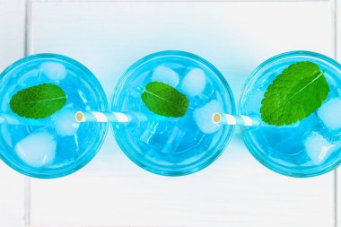 Mavi buz ve mavi bir tabloda bir beyaz tahta tahtada bardaklarda nane kokteyli. Üstten Görünüm.