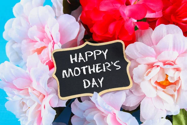Peonías rosadas con una pizarra sobre una mesa de madera azul. Una postal para las vacaciones. Feliz día de la madre . — Foto de Stock
