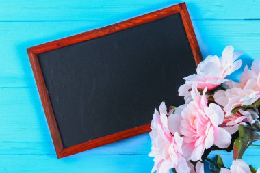 Pembe peonies mavi ahşap bir masa bir kara tahta ile. Kartpostal tatil için. Kopyalama alanı.