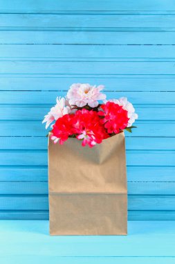 Pembe peonies mavi ahşap bir masa üzerinde bir zanaat paketindeki. Kartpostal tatil için.