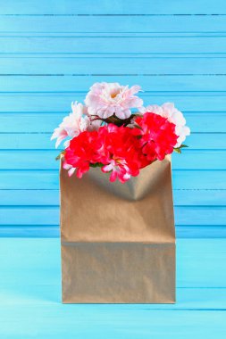 Pembe peonies mavi ahşap bir masa üzerinde bir zanaat paketindeki. Kartpostal tatil için.