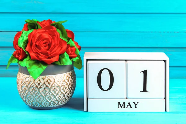 Białe drewniane kalendarz z tekstem: 1 maja. DIY róża na niebieskim drewnianym stole. Święto pracy i wiosna. — Zdjęcie stockowe