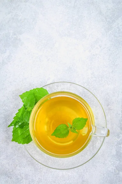Blad av färska gröna nässlor och en klart glas kopp växtbaserade nässlor te på en grå betong bord. Ovanifrån. — Stockfoto