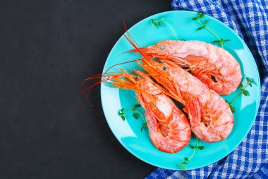 Büyük Kraliyet ham dondurulmuş karides kekik ile mavi tabakta ve fesleğen beton bir tablo. Kırmızı karides. Üstten Görünüm.