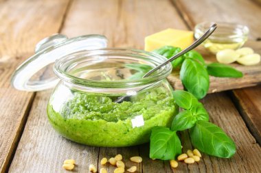 Ev yapımı pesto sos. Malzemeler. Peynir, sarımsak, fesleğen, çam fıstığı, zeytin yağı eski ahşap masa.