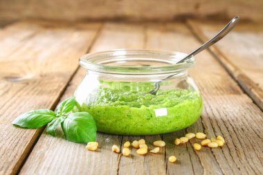 Ev yapımı pesto sos. Malzemeler. Peynir, sarımsak, fesleğen, çam fıstığı, zeytin yağı eski ahşap masa.