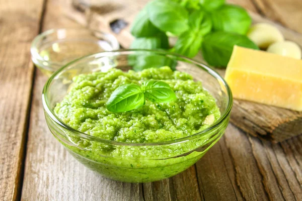 Salsa di pesto fatta in casa. Ingredienti. Formaggio, aglio, basilico, pinoli, olio d'oliva su un vecchio tavolo di legno . — Foto Stock