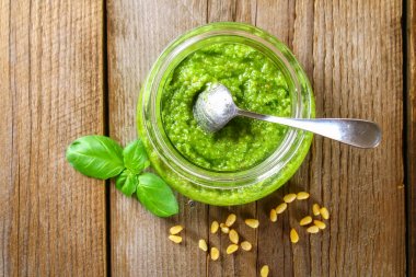 Ev yapımı pesto sos. Malzemeler. Peynir, sarımsak, fesleğen, çam fıstığı, zeytin yağı eski ahşap masa.