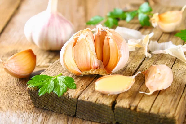 Heads of garlic with parsley on a wooden table.