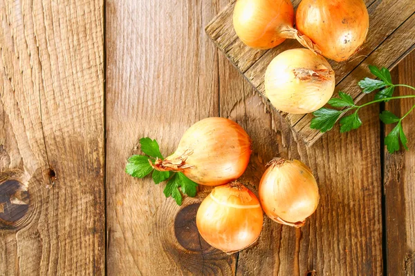 Yellow onion with parsley on a wooden table. — Stock Photo, Image