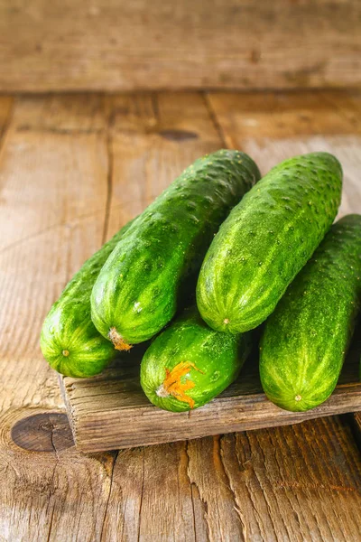 Fresh cucumbers with a leaf on an old wooden table. — Stock Photo, Image