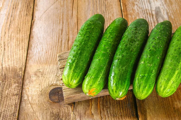 Fresh cucumbers with a leaf on an old wooden table. — Stock Photo, Image