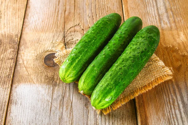 Fresh cucumbers with a leaf on an old wooden table. — Stock Photo, Image