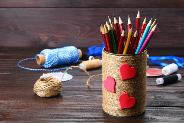 Bank for pencils with hearts wrapped with string on a wooden tab