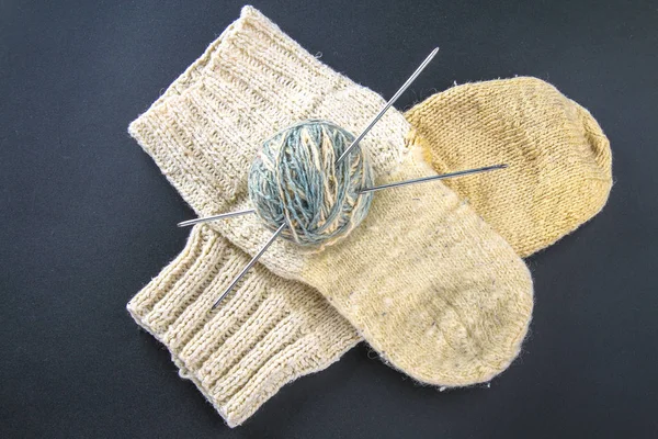 Ein Wollknäuel mit Stricknadeln und Socken auf einem grauen Tisch. Handarbeit. — Stockfoto