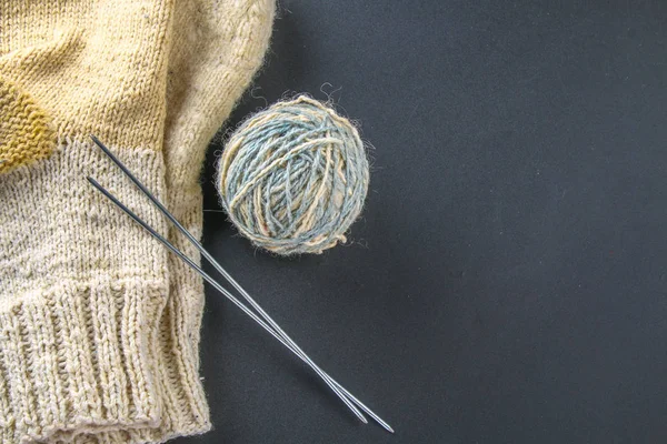 A ball of wool with knitting needles and socks on a gray table. Needlework. — Stock Photo, Image