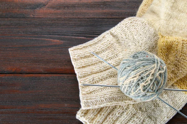 Ein Wollknäuel mit Stricknadeln und gestrickten Socken auf einem Holztisch. Handarbeit. — Stockfoto