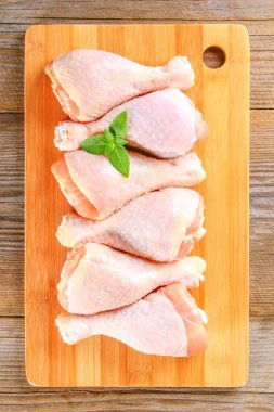 Bir kesme tahtası üzerinde eski bir ahşap masa üzerinde çiğ tavuk budu.