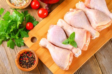 Bir kesme tahtası üzerinde eski bir ahşap masa üzerinde çiğ tavuk budu.