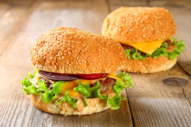Bun, köftesi, salata, kırmızı soğan ve domates eski bir ahşap masa üzerinde oluşan lezzetli ev yapımı hamburger.
