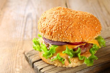 Bun, köftesi, salata, kırmızı soğan ve domates eski bir ahşap masa üzerinde oluşan lezzetli ev yapımı hamburger.